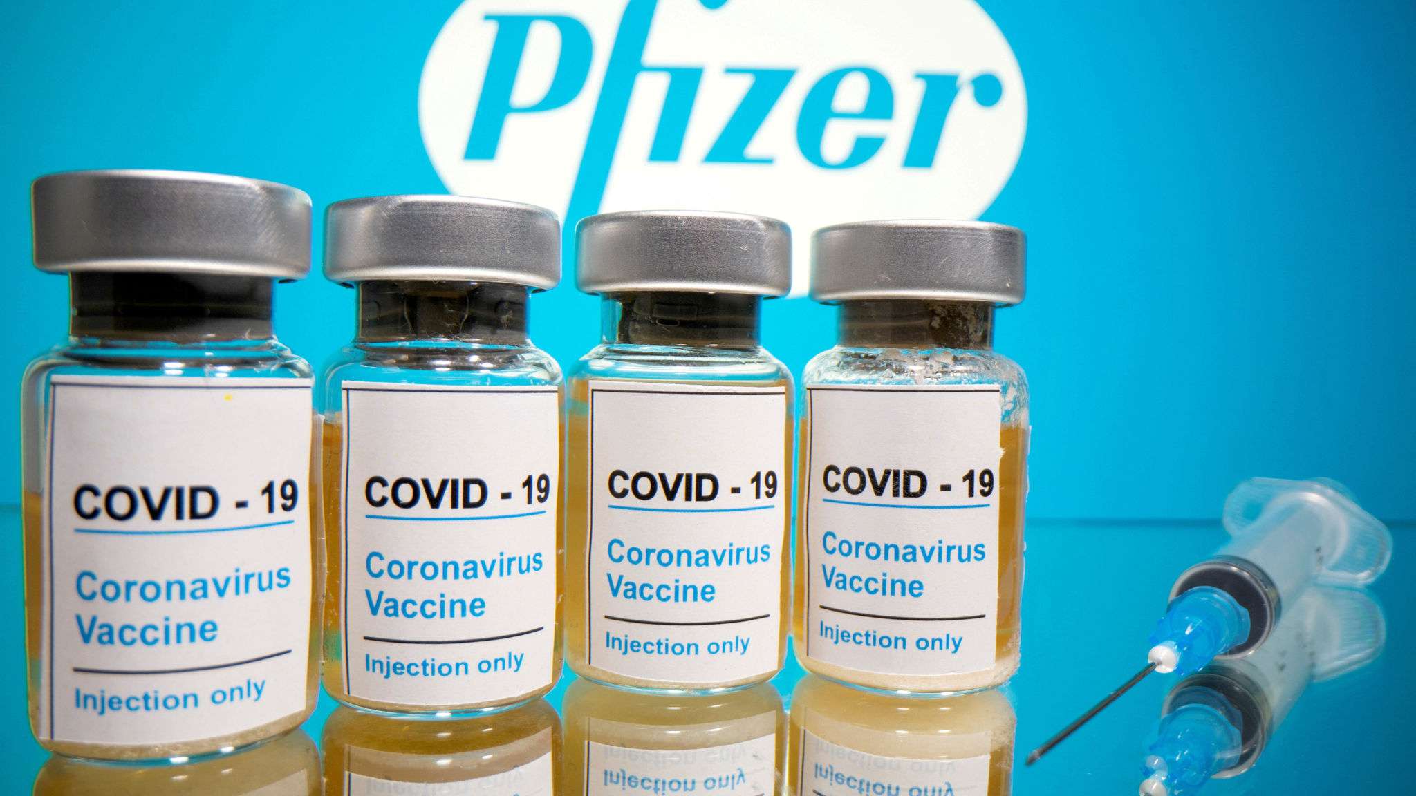 FILE PHOTO: Vials and medical syringe are seen in front of Pfizer logo in this illustration