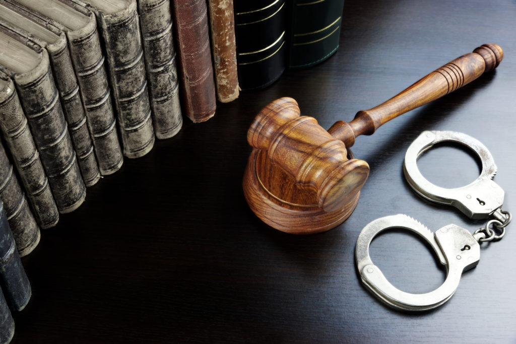 Judges Gavel, Handcuffs And Old Book On The Black Table