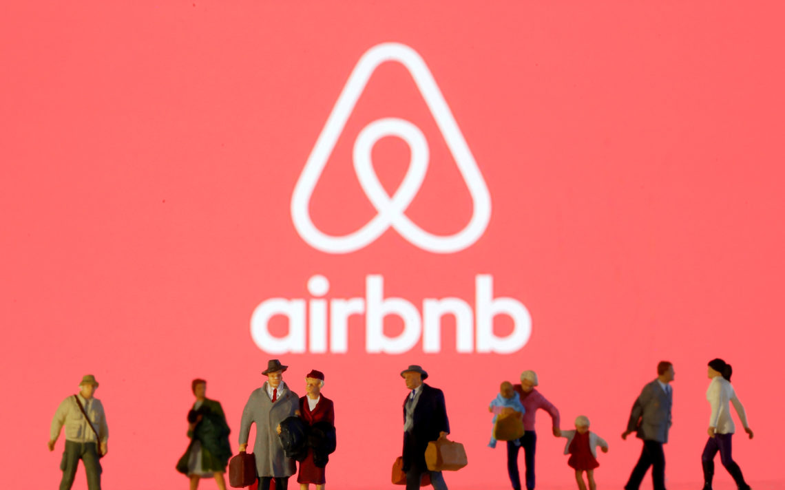 FILE PHOTO: Small toy figures are seen in front of diplayed Airbnb logo