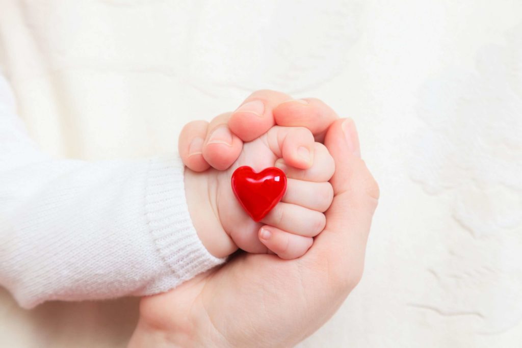 hands of mother and baby holding heart