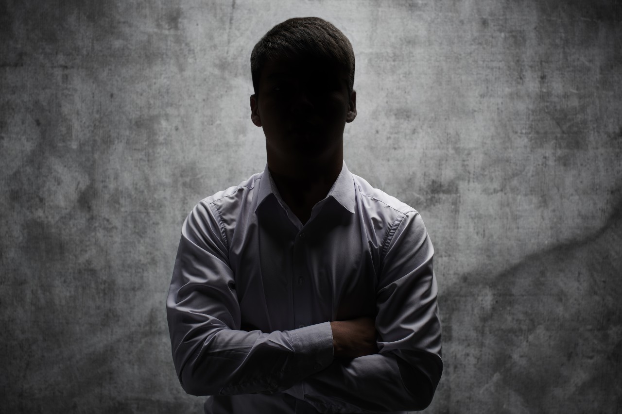 anonymous-man-business-shirt-with-arms-crossed-against-dark-background