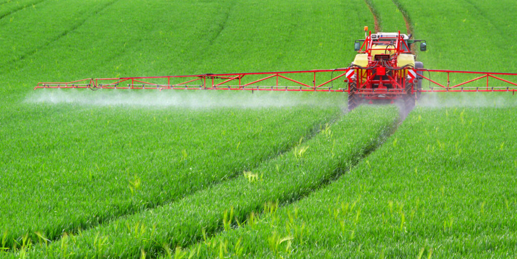 Traktor mit Feldspritze beim ausbringen von Pflanzenschutzmittel