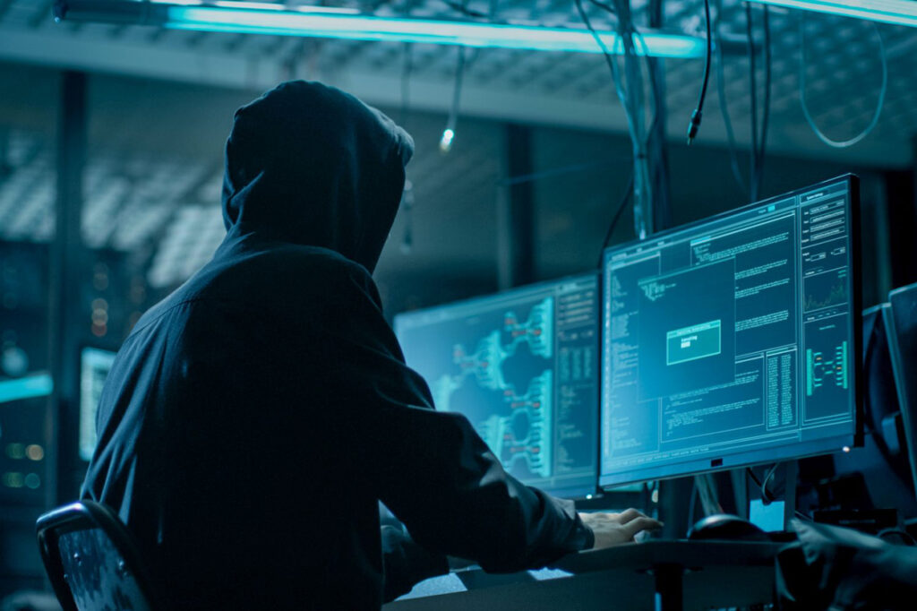 Shot from the Back to Hooded Hacker Breaking into Corporate Data