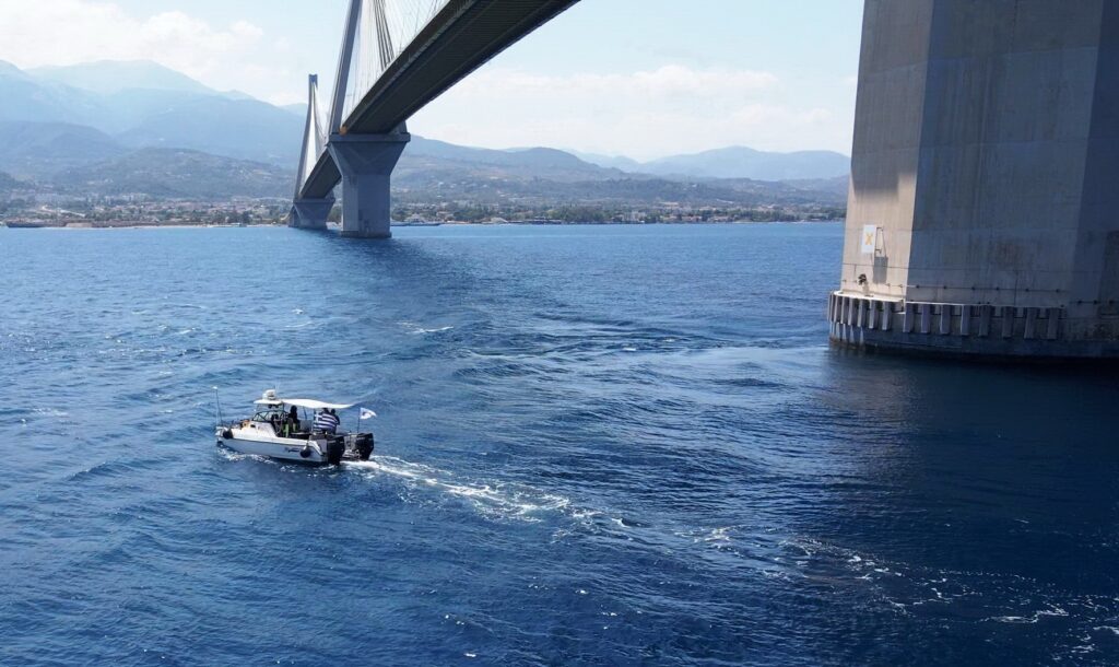 Η ΓΕΦΥΡΑ, μέλος του Δικτύου VINCI Highways, ανακοινώνει ότι ολοκληρώθηκαν με επιτυχία οι υποθαλάσσιες επιθεωρήσεις της λιθορριπής προστασίας περιμετρικά των θεμελίων των πυλώνων. Οι εν λόγω επιθεωρήσεις διενεργούνται κάθε 8 χρόνια και είναι εξαιρετικά σημαντικές καθώς σκοπός τους είναι να εξεταστεί η κατάσταση της λιθορριπής που προστατεύει τη θεμελίωση των πυλώνων της Γέφυρας έναντι υποσκαφής, από τα ισχυρά ρεύματα που αναπτύσσονται περιμετρικά των υποθαλάσσιων θεμελίων. Η επιθεώρηση διεξήχθη με τη συμμετοχή εξειδικευμένου τεχνικού προσωπικού και χρήση τεχνολογίας αιχμής όπως ρομποτικά οχήματα (ROV) και εξελιγμένα συστήματα συλλογής δεδομένων και εντοπισμού θέσης (USBL). Επισημαίνεται ότι η διεξαγωγή των υποθαλάσσιων ερευνών σε βάθη μέχρι 65μ. από την επιφάνεια της θάλασσας είναι εξαιρετικά απαιτητική λόγω των ιδιαίτερων συνθηκών που επικρατούν στο στενό Ρίου-Αντιρρίου όπως η θολότητα του νερού, τα ισχυρά θαλάσσια ρεύματα και οι συχνοί άνεμοι που πνέουν στην περιοχή. Έπειτα από 19 χρόνια από την ολοκλήρωση της κατασκευής και 3 κύκλους υποθαλάσσιων επιθεωρήσεων, η αξιολόγηση των διαθέσιμων δεδομένων επιβεβαιώνει την άρτια μελέτη και κατασκευή του Έργου με υψηλά πρότυπα ποιότητας. Η δε συνέχιση των επιθεωρήσεων για την αξιολόγηση ενός τόσο κρίσιμου στοιχείου έχει ενσωματωθεί στο πρόγραμμα των μελλοντικών επιθεωρήσεων. Ο Διευθύνων Σύμβουλος της ΓΕΦΥΡΑ Πάνος Λούκας δήλωσε σχετικά: «Η ολοκλήρωση ενός τόσου δύσκολου εγχειρήματος αποδεικνύει την σημασία που δίνουμε στη διασφάλιση της ακεραιότητας και ανθεκτικότητας του Έργου. Η εισαγωγή καινοτόμων τεχνικών λύσεων και εξειδικευμένων μεθόδων αποτελούν μέρος της μόνιμης δέσμευσης της ΓΕΦΥΡΑ, μέλος του δικτύου της VINCI Highways μίας από τις μεγαλύτερες εταιρείες διαχείρισης αυτοκινητοδρόμων υπό παραχώρηση παγκοσμίως, στην ασφάλεια και δομική συντήρηση του Έργου. Από την έναρξη λειτουργίας της Γέφυρας το 2004 μέχρι σήμερα έχουμε υλοποιήσει επενδύσεις της τάξης των €50 εκατομμυρίων και συνεχίζουμε να το πράττουμε. Στη ΓΕΦΥΡΑ εργαζόμαστε με όραμα την προαγωγή της θετικής κινητικότητας, συμβάλλοντας μέσω της συνεχούς διαθεσιμότητας του Έργου στη βιώσιμη οικονομική ανάπτυξη των τοπικών κοινωνιών στις δύο πλευρές του Στενού».
