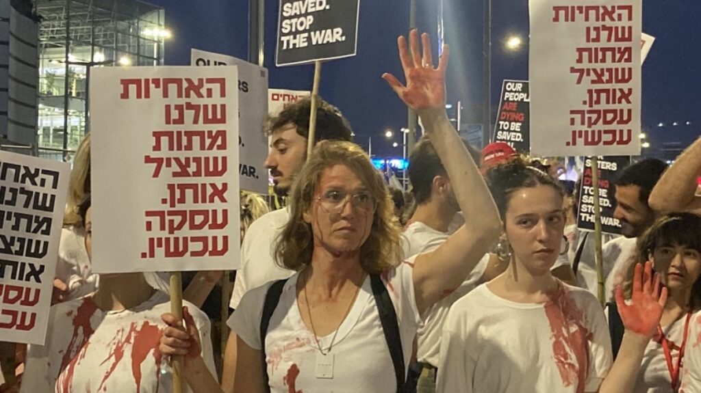 «Συμφωνία για τους ομήρους τώρα», απαιτούσε διαδηλώτρια που είχε μεταμφιεστεί σε άγαλμα της Ελευθερίας, ανάμεσα σε θάλασσα σημαιών του Ισραήλ.