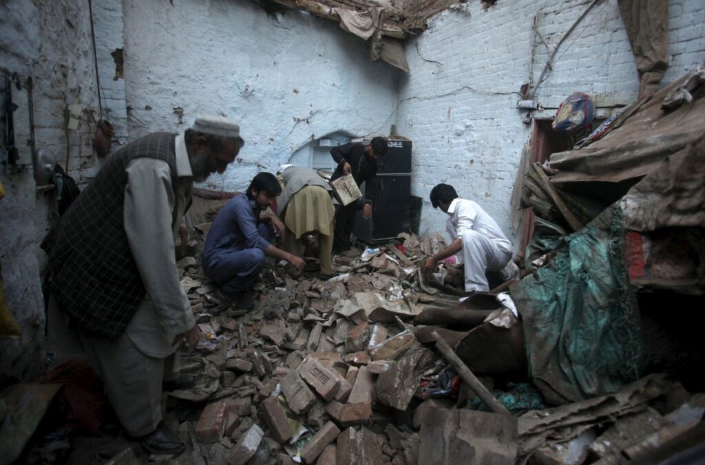 Residents search for belongings in the rubbles of a house after it was damaged by an earthquake in Peshawar